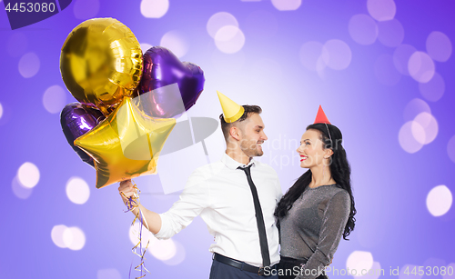 Image of happy couple with party caps and balloons