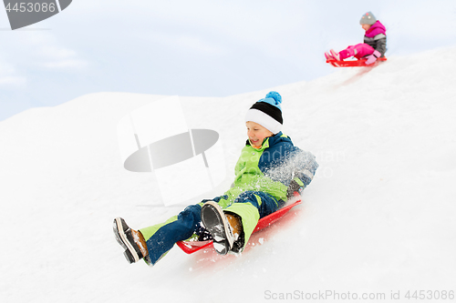 Image of happy kids sliding on sleds down hill in winter