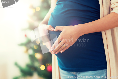 Image of close up of pregnant woman making heart on belly