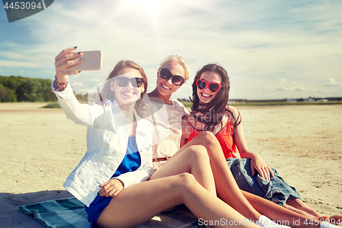 Image of group of smiling women taking selfie on beach