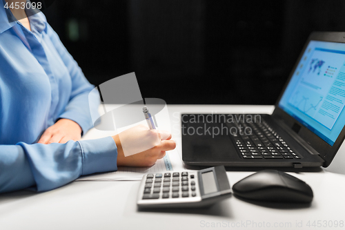 Image of businesswoman with papers working at night office