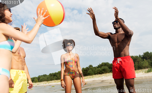 Image of friends playing with beach ball in summer