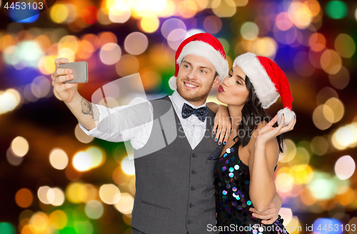 Image of couple in santa hats taking selfie at christmas