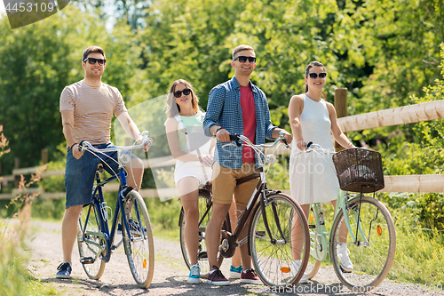 Image of happy friends riding fixed gear bicycles in summer