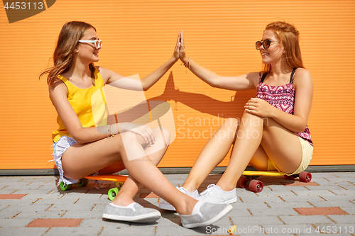 Image of teenage girls with skateboards making high five