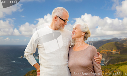 Image of happy senior couple hugging over big sur coast