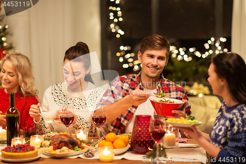 Image of happy friends having christmas dinner at home