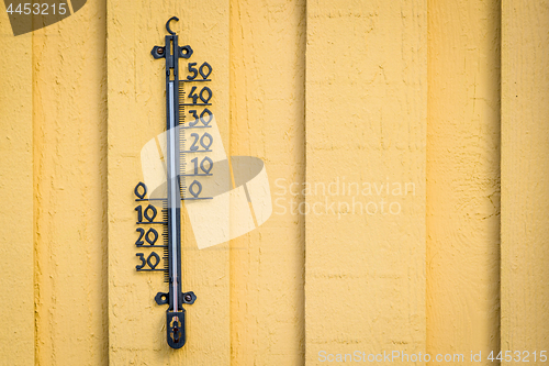 Image of Weather thermometer hanging on a yellow wall