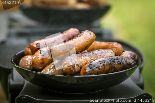 Image of Grilled sausages on a plate at an outdoor barbecue
