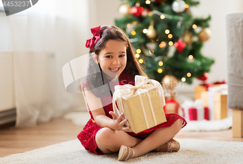 Image of happy girl with christmas gift at home