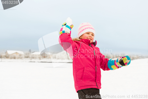 Image of happy girl playing and throwing snowball in winter