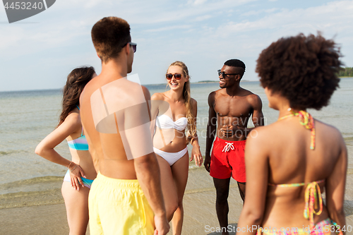 Image of happy friends hugging on summer beach