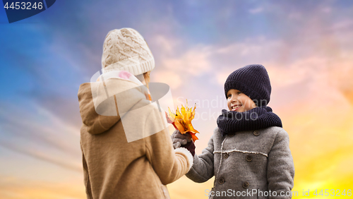 Image of kids with autumn maple leaves over sky background