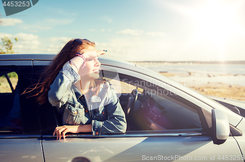 Image of happy teenage girl or young woman in car