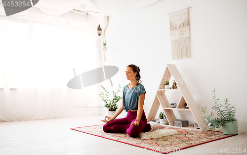 Image of woman meditating in lotus pose at yoga studio