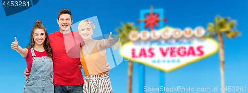 Image of happy friends showing thumbs up at las vegas sign