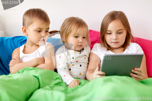 Image of little kids with tablet pc in bed at home