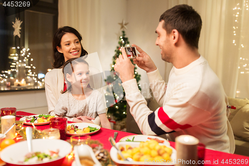 Image of happy family taking picture at christmas dinner