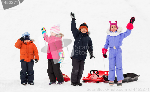 Image of happy kids with sleds waving hands in winter