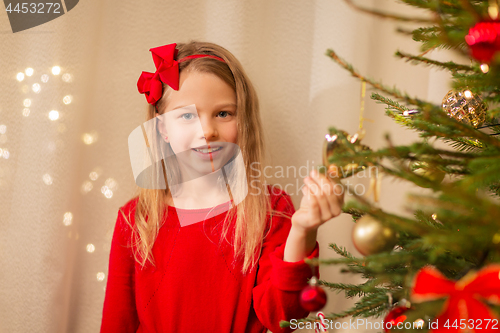 Image of happy girl in red decorating christmas tree