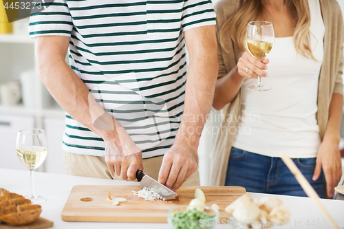 Image of couple cooking food and drinking wine at home