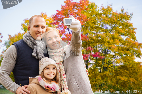 Image of family taking selfie by camera in autumn park