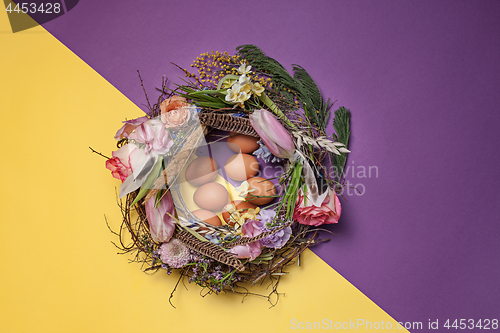 Image of Easter card. Painted Easter eggs in nest on yellow background