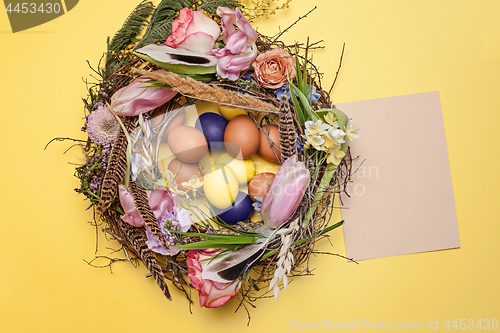 Image of Easter card. Painted Easter eggs in nest on yellow background