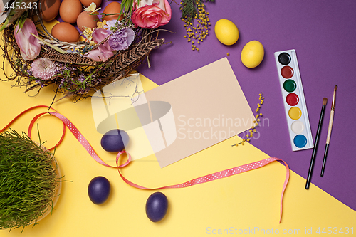 Image of Easter card. Painted Easter eggs in nest on yellow background