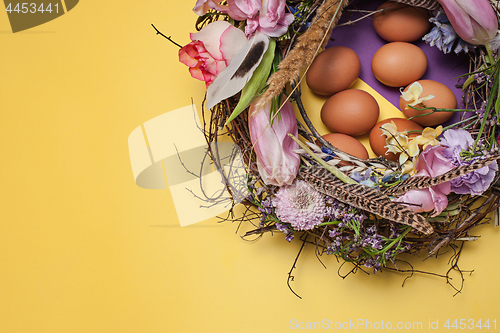 Image of Easter card. Painted Easter eggs in nest on yellow background