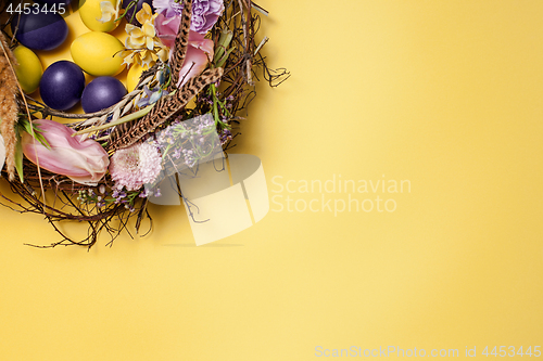 Image of Easter card. Painted Easter eggs in nest on yellow background