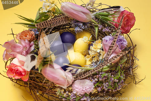 Image of Easter card. Painted Easter eggs in nest on yellow background