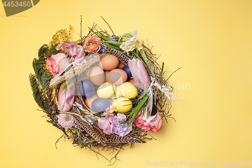 Image of Easter card. Painted Easter eggs in nest on yellow background