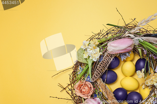 Image of Easter card. Painted Easter eggs in nest on yellow background