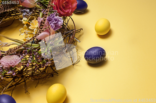 Image of Easter card. Painted Easter eggs in nest on yellow background