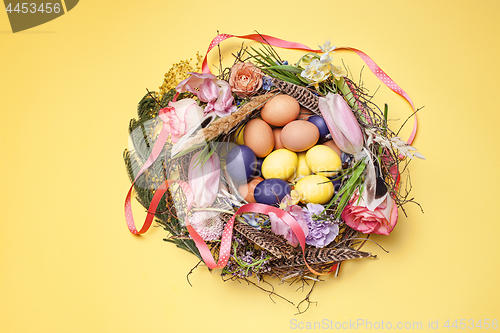 Image of Easter card. Painted Easter eggs in nest on yellow background