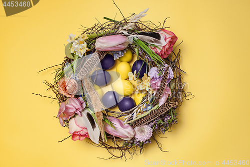 Image of Easter card. Painted Easter eggs in nest on yellow background