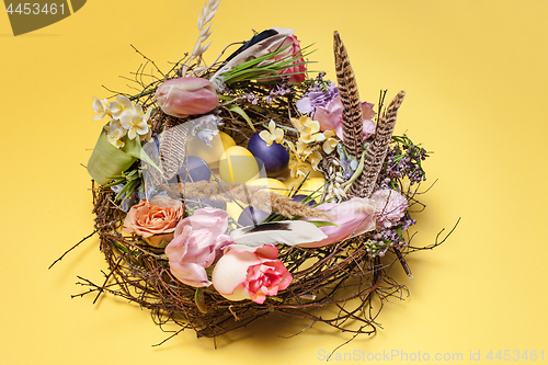 Image of Easter card. Painted Easter eggs in nest on yellow background