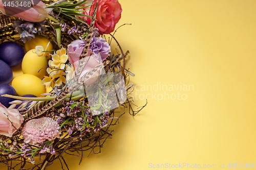 Image of Easter card. Painted Easter eggs in nest on yellow background