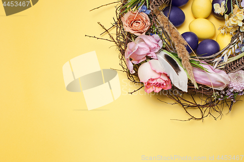 Image of Easter card. Painted Easter eggs in nest on yellow background