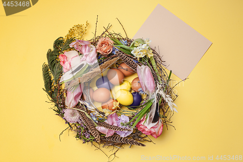 Image of Easter card. Painted Easter eggs in nest on yellow background