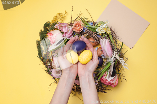 Image of Easter card. Painted Easter eggs in nest on yellow background