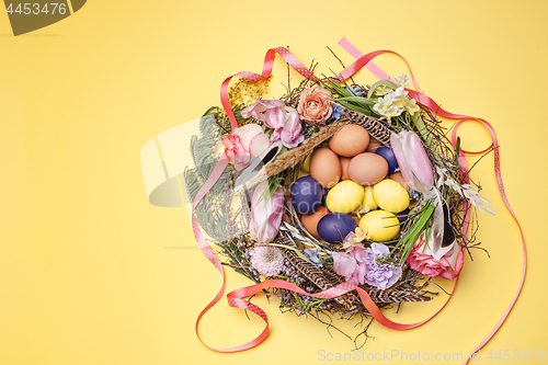 Image of Easter card. Painted Easter eggs in nest on yellow background