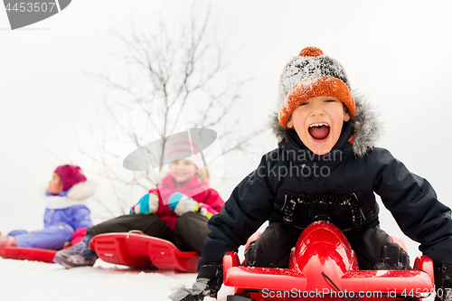 Image of happy kids sliding on sleds in winter