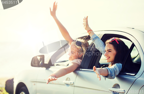 Image of happy teenage girls or women in car at seaside