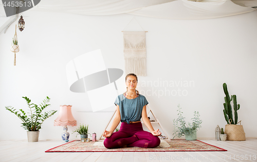 Image of woman meditating in lotus pose at yoga studio