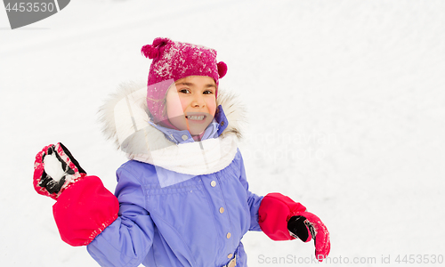 Image of happy girl playing and throwing snowball in winter