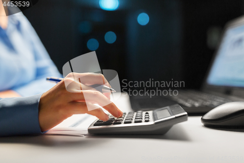 Image of businesswoman with calculator at night office