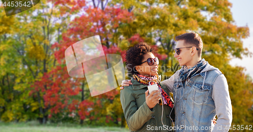 Image of couple listens music by smartphone in autumn park