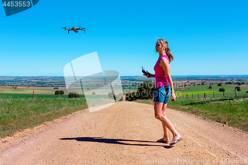 Image of Woman flying a drone in rural landscape